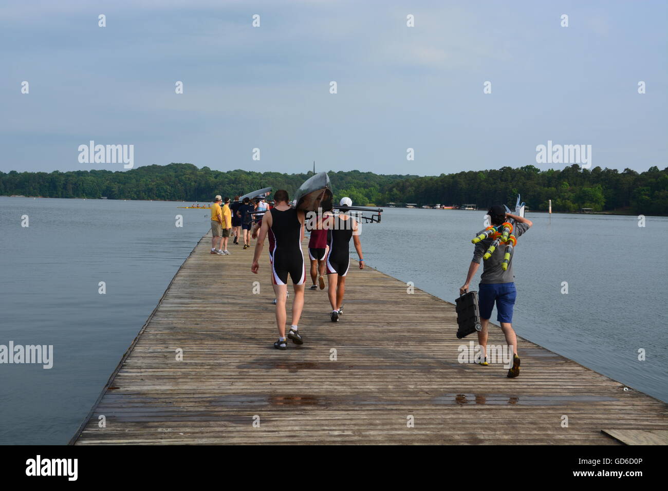 Men's college rowing team carry a boat down the dock to launch for a regatta at Atlanta's former Olympic site at Lake Lanier in 2014. Stock Photo