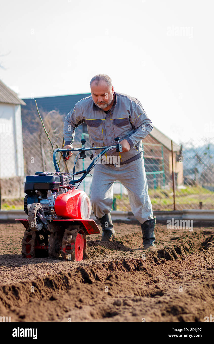 Man working in the garden with Garden Tiller. Garden tiller to work