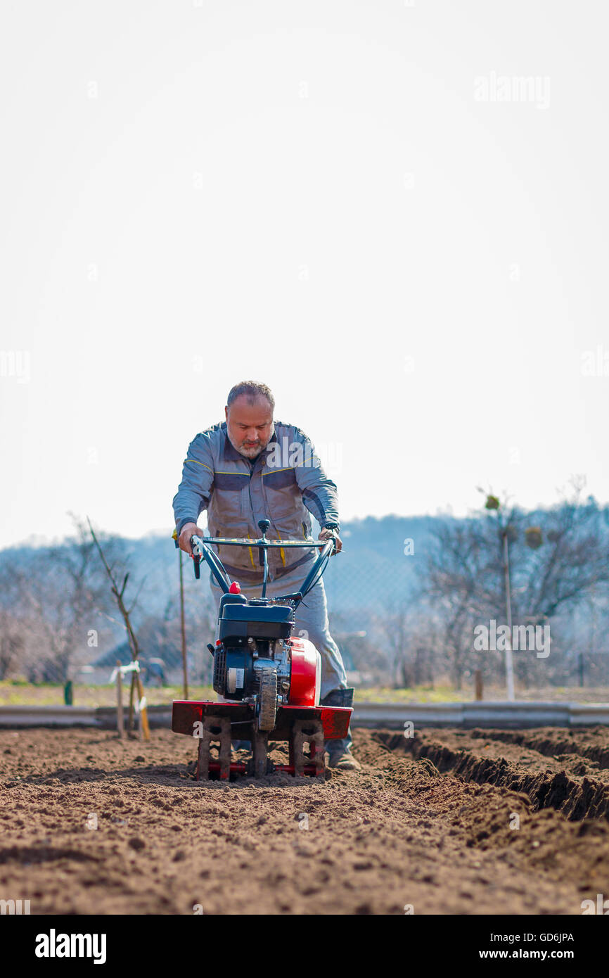 Man working in the garden with Garden Tiller. Garden tiller to work. Man with tractor