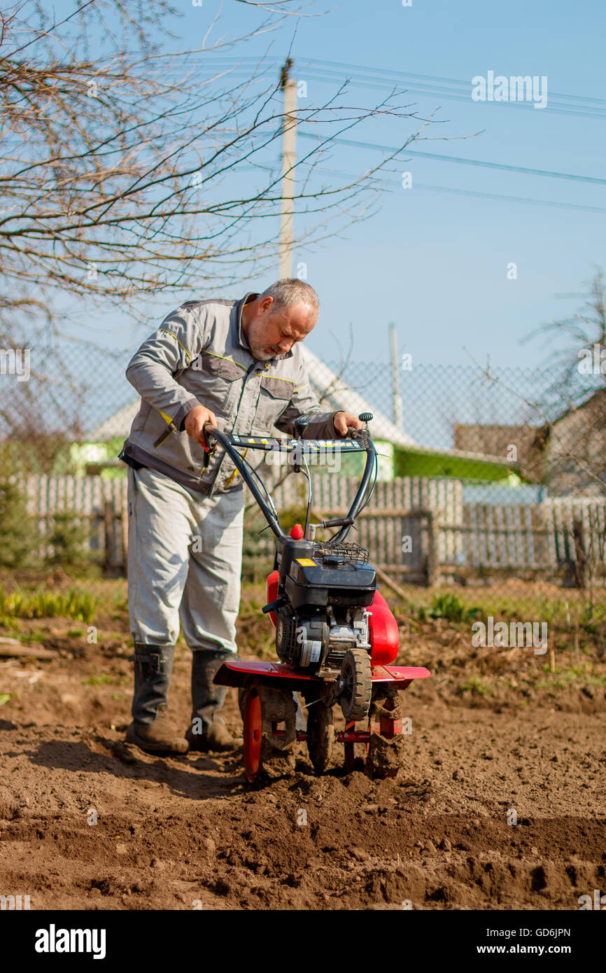 Man working in the garden with Garden Tiller. Garden tiller to work. Man with tractor