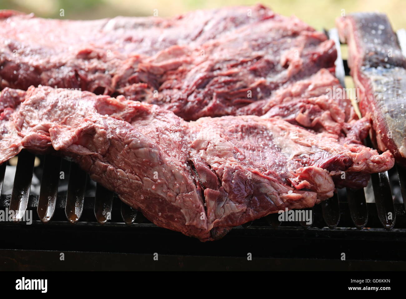 Raw Beef Meat on the Grill, Close Up. Sinta, Raw meat, raw flesh. Red meat on the grill. Rare sinta, fresh salted asado at the beginning of the holida Stock Photo