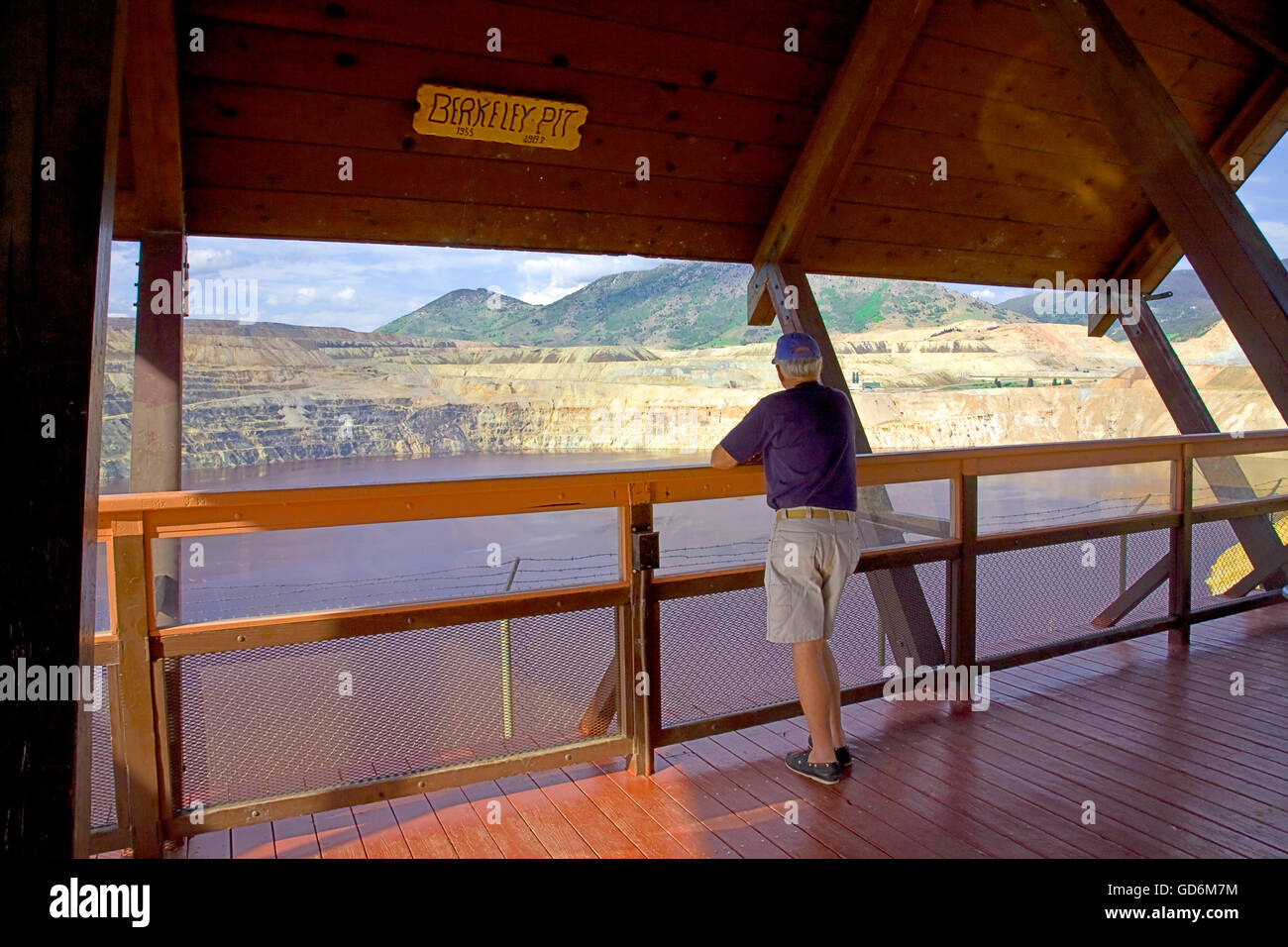 Man views one of the nation's Superfund Sites, the Berkeley Pit, a former open pit copper mine in Butte, Montana.  One mile long by half a mile wide with an approximate depth of 1,780 feet (540 m), it is filled to a depth of about 900 feet (270 m) with wa Stock Photo