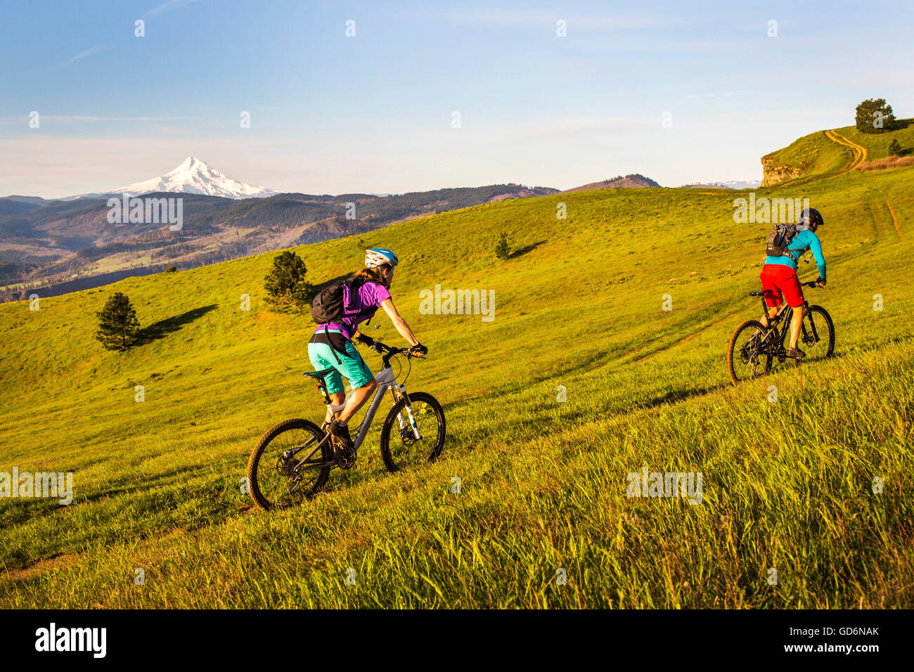 Two young women ride mountain bikes up 