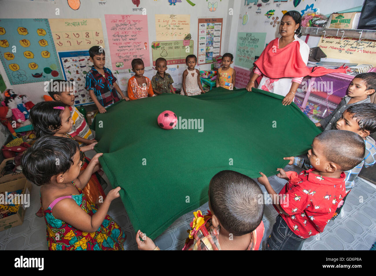 Urban Slum kids go to the Pre-school. Dhaka, Bangladesh. Seen here students playing a ball game with teacher. Stock Photo