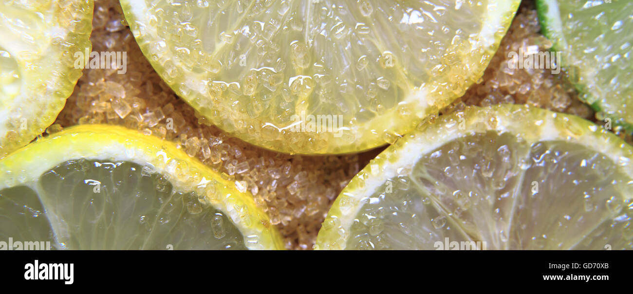 view on slices of limes and lemons mixed with cane sugar placed flat on the ground Stock Photo