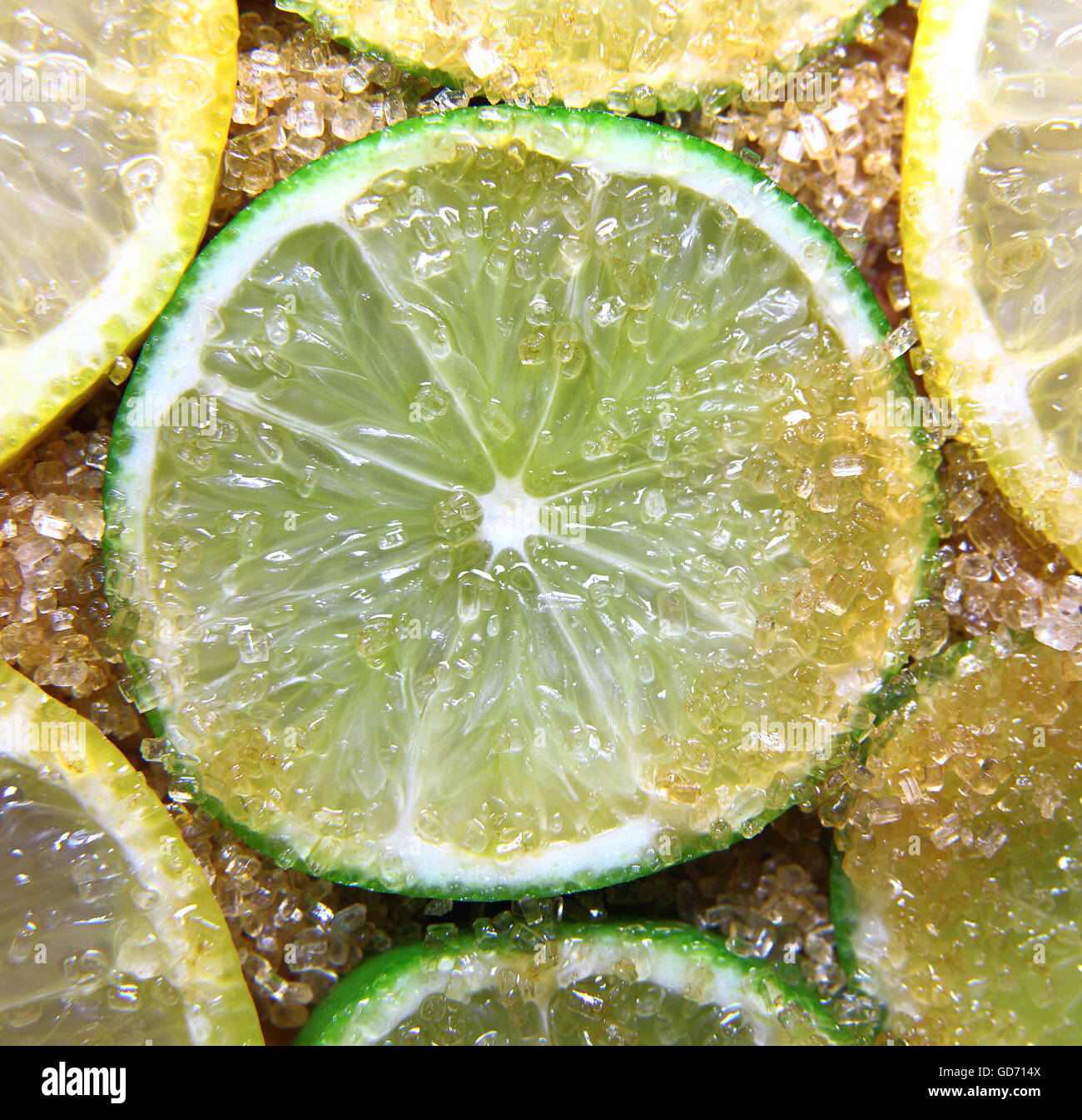 view on slices of limes and lemons mixed with cane sugar placed flat on the ground Stock Photo