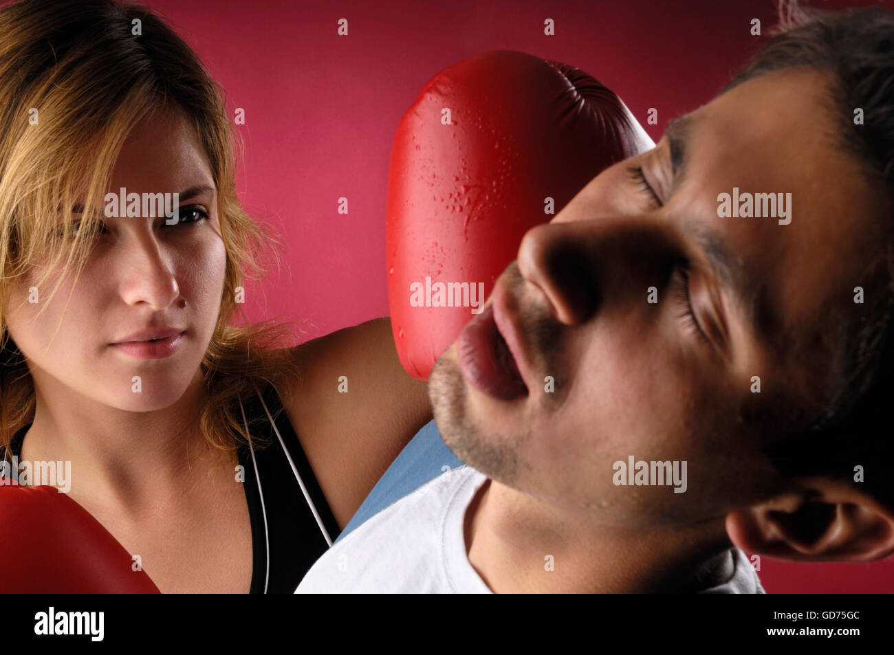 Young woman boxer punching a young man on his face knocking him down
