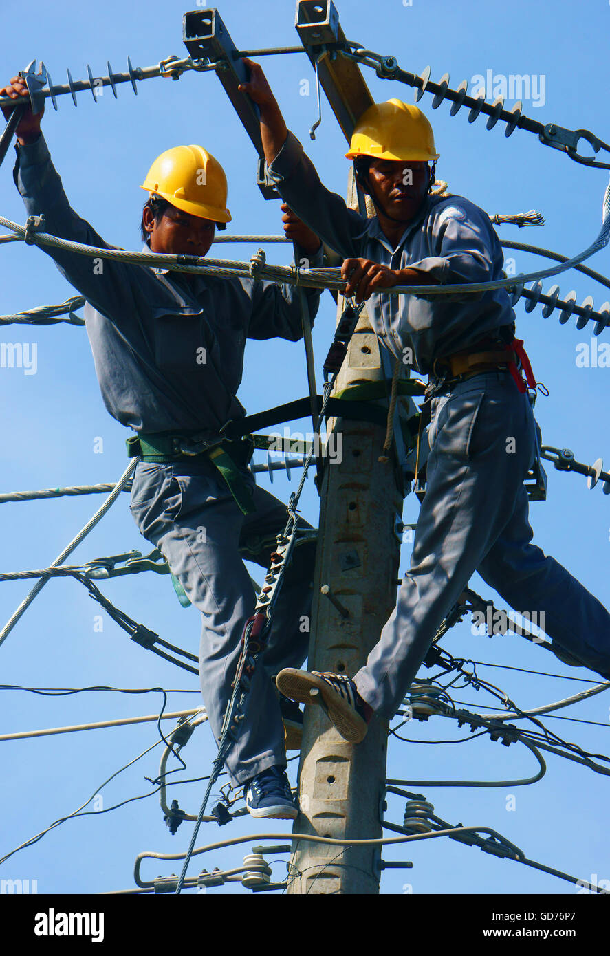 Asian electrician climb high in pole to work, lineman with cable
