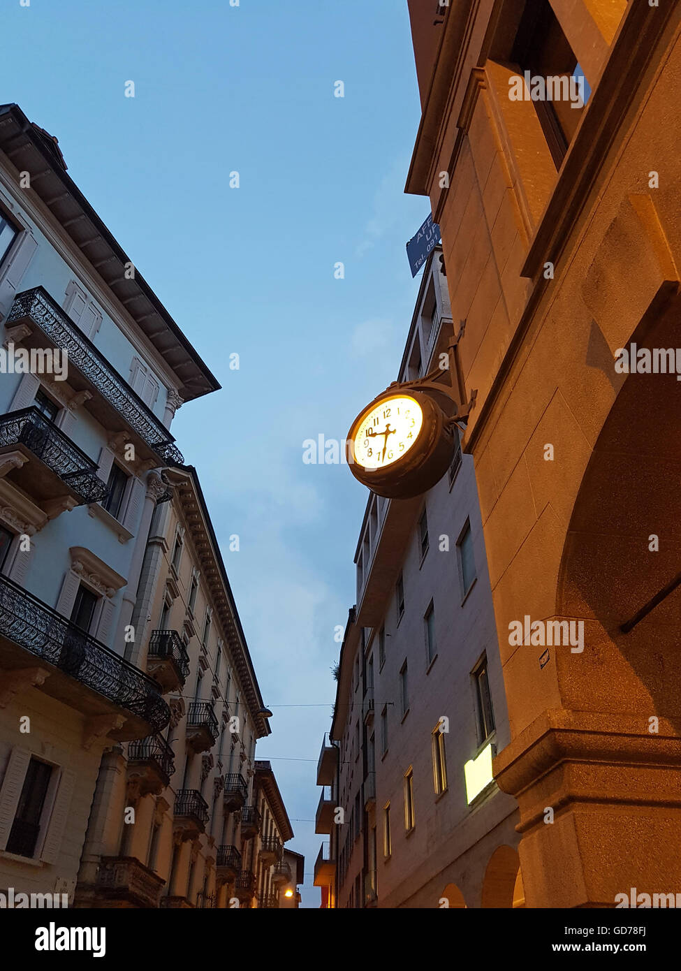 Old european street with illuminated wall clock at night Stock Photo