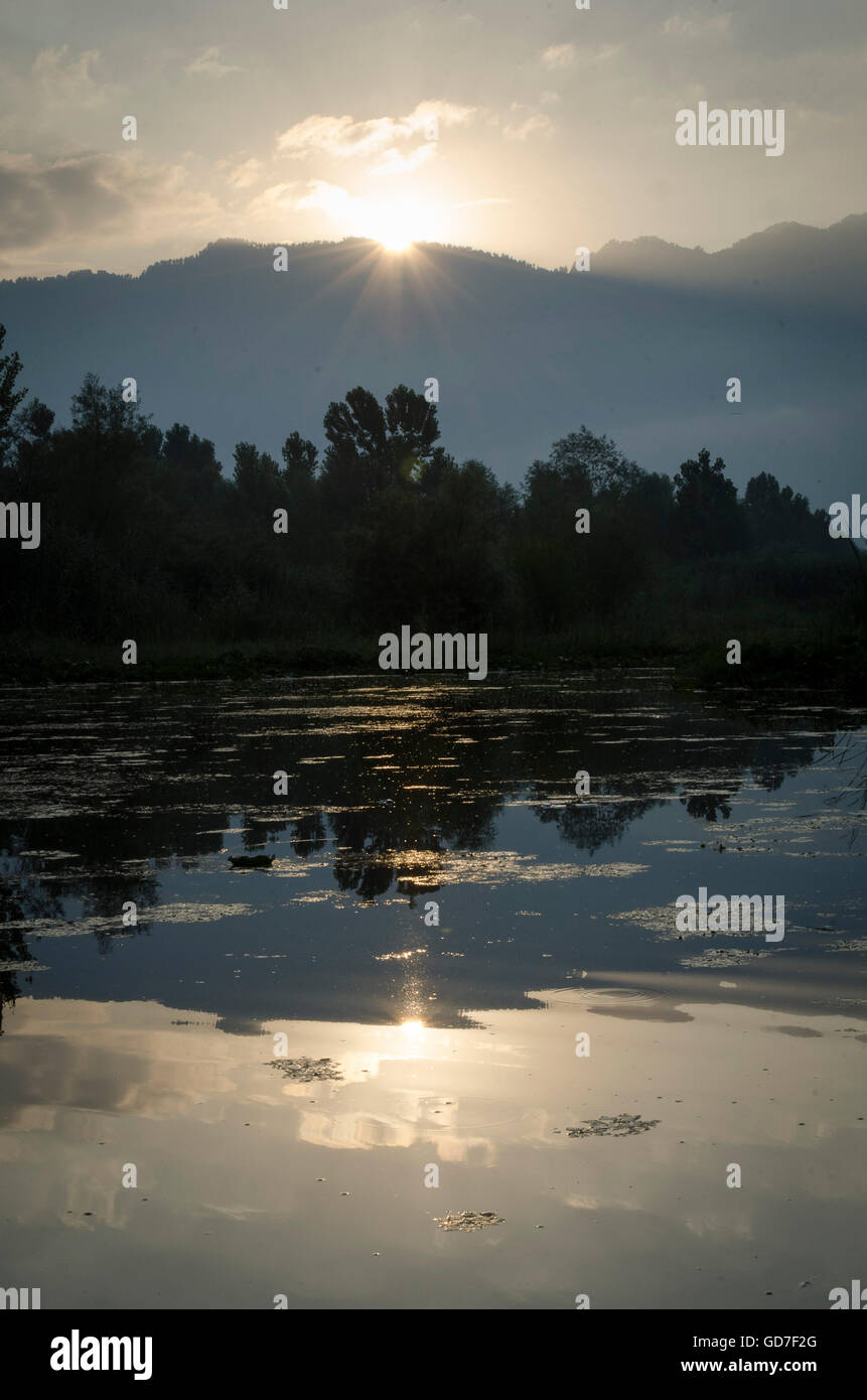 Sun rising over mountains and reflected in Dal Lake, Srinagar, Jammu