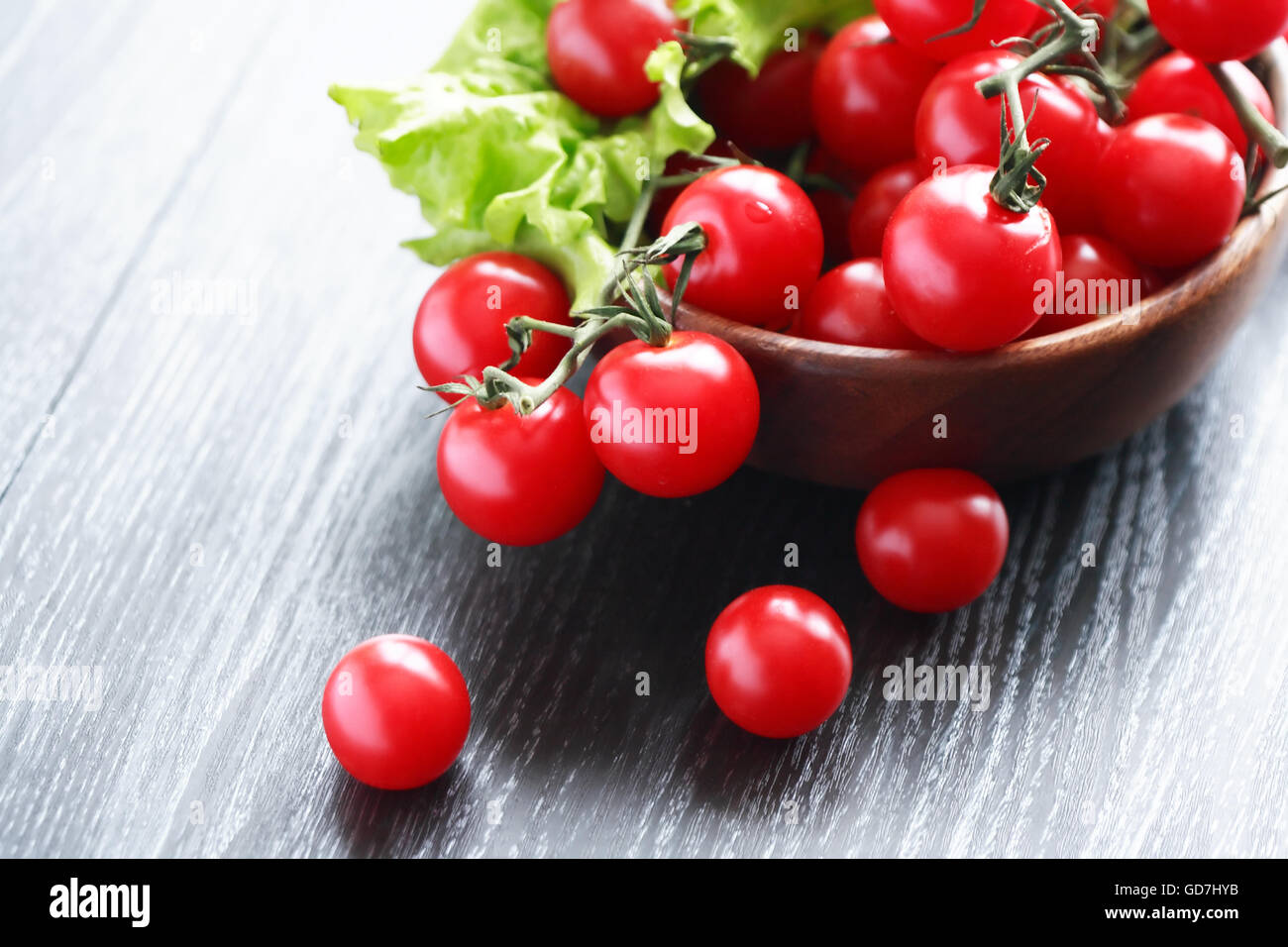 Wooden bowl with cherry tomatoes on black table Stock Photo - Alamy