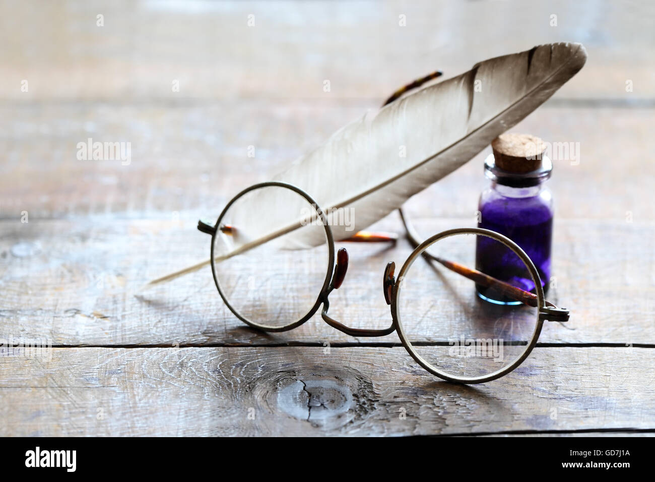 Art concept. Closeup of old spectacles near quill and inkpot on wooden