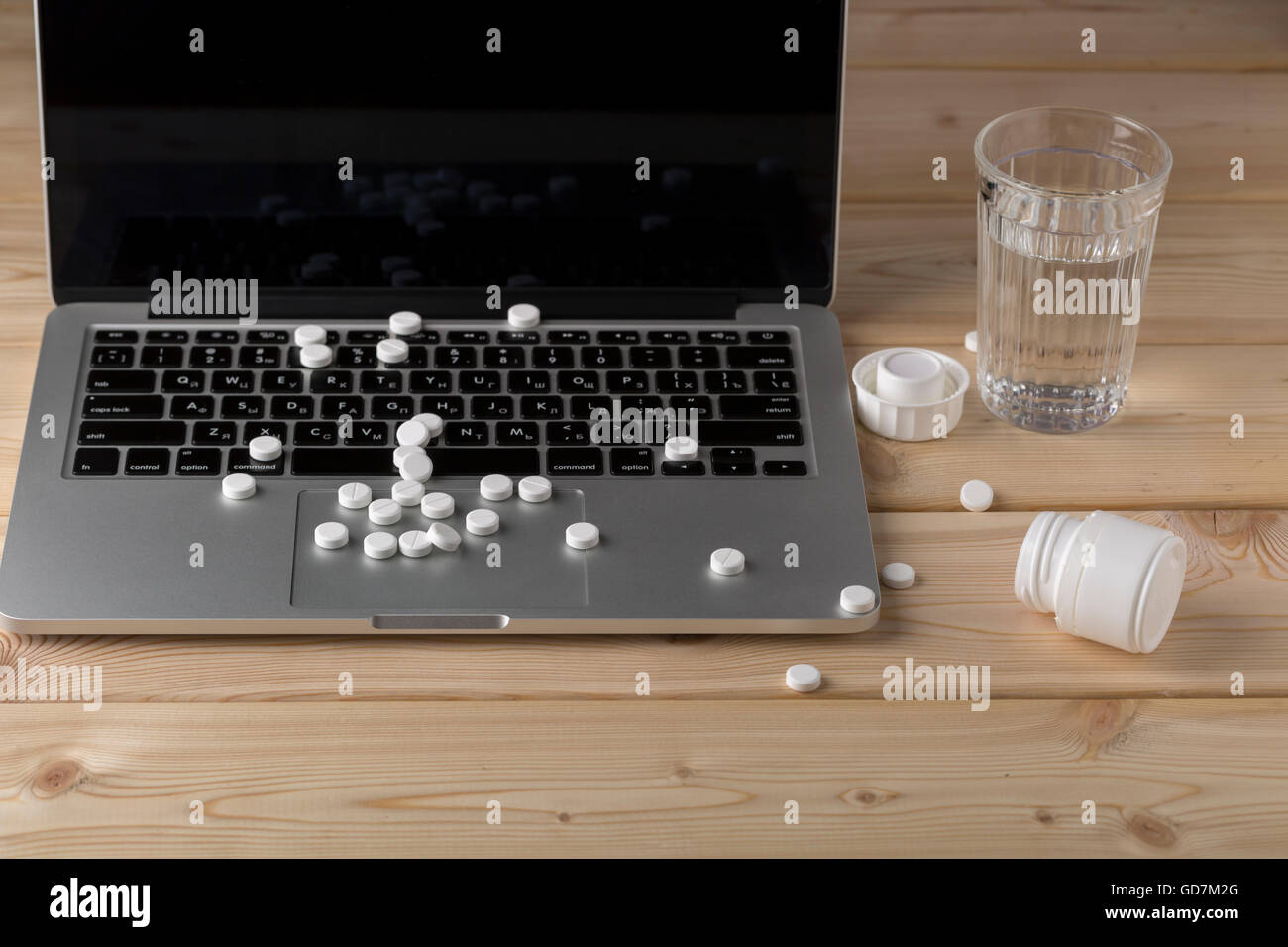 Scattered white pills on the laptop keyboard Stock Photo
