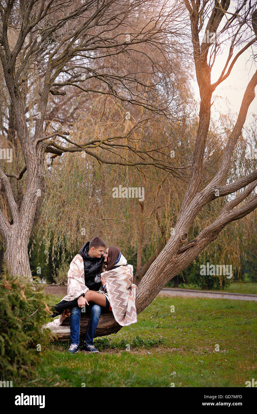 man and woman walking in autumn park covered with a blanket Stock Photo