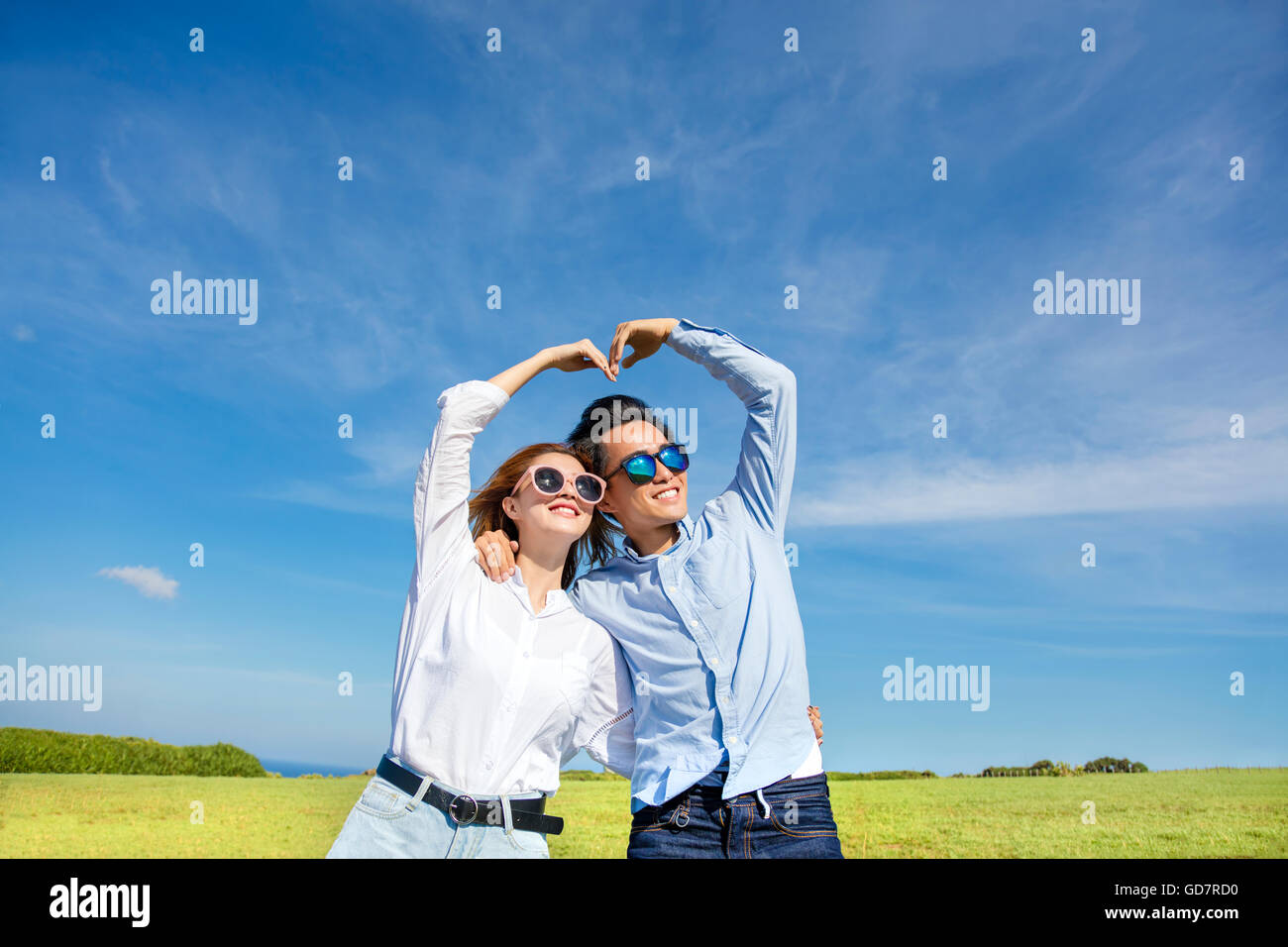Happy playful young  couple forming love shape Stock Photo