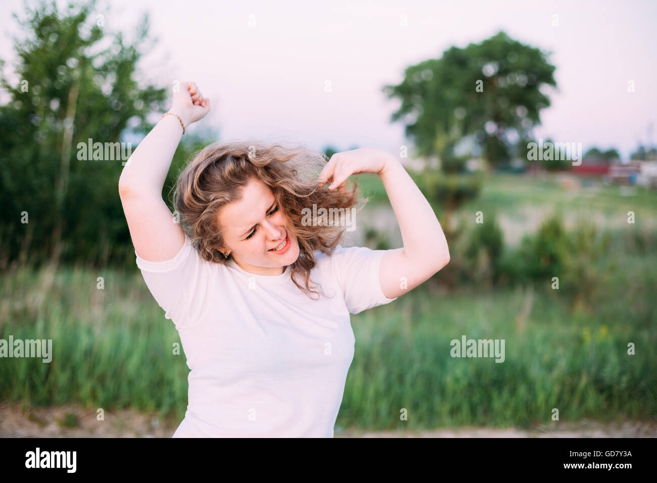 Portrait Of Funny Beautiful Plus Size Young Woman Girl In White Shirt Dancing In Summer Field Meadow. Spring, Outdoor Portrait Stock Photo