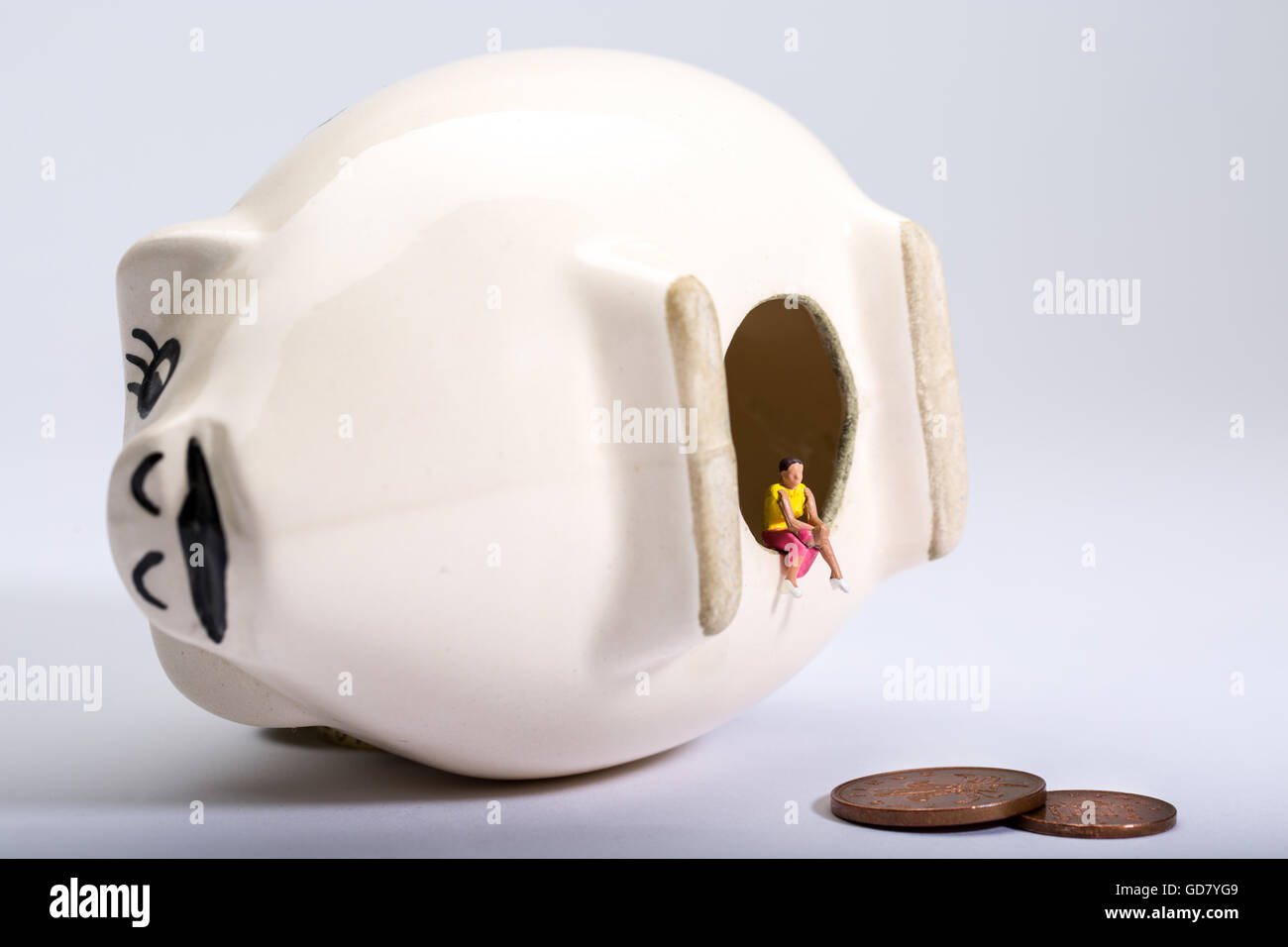 concept image of a lone figure with an empty piggy bank to illustrate ...