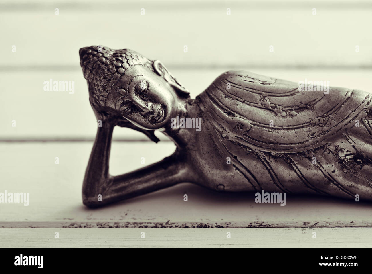 closeup of a representation of the buddha laying down, on a pale green rustic background Stock Photo