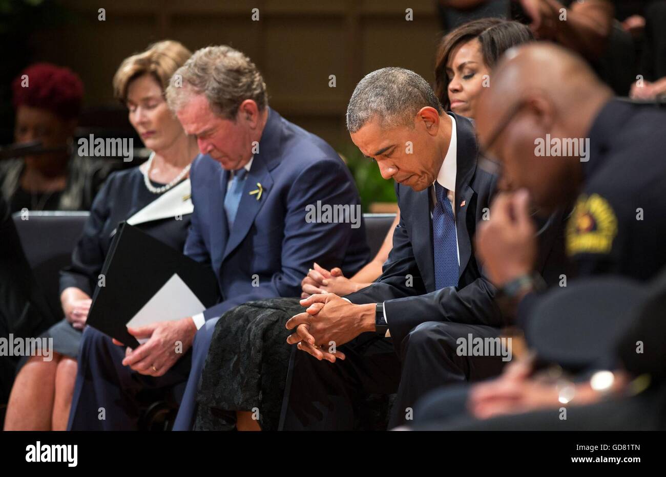 U.S President Barack Obama bows his head alongside former President George W. Bush during a memorial service for the five police officers who were killed by a sniper during protests July 11, 2016 in Dallas, Texas. Stock Photo