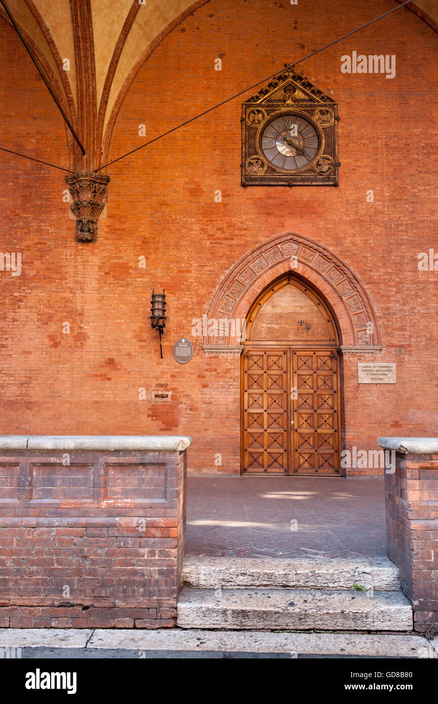 Door and the clock of the ancient Palazzo della mercanzia (14th century), Bologna. Stock Photo