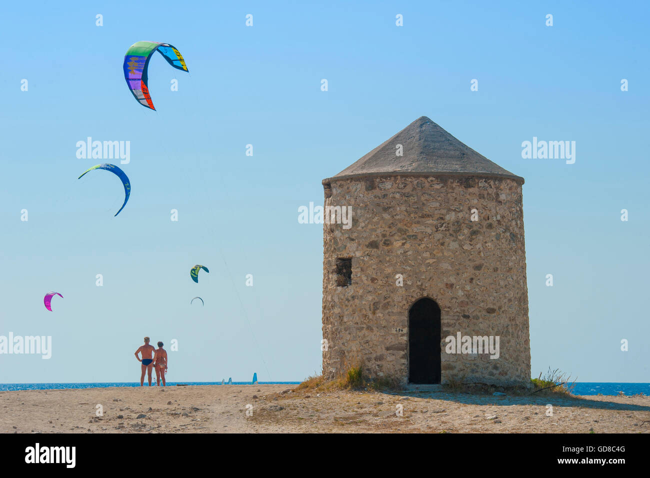 Old windmills on a beach populated by windsurfers and kitesurfers in Lefkada, Lefkas Stock Photo