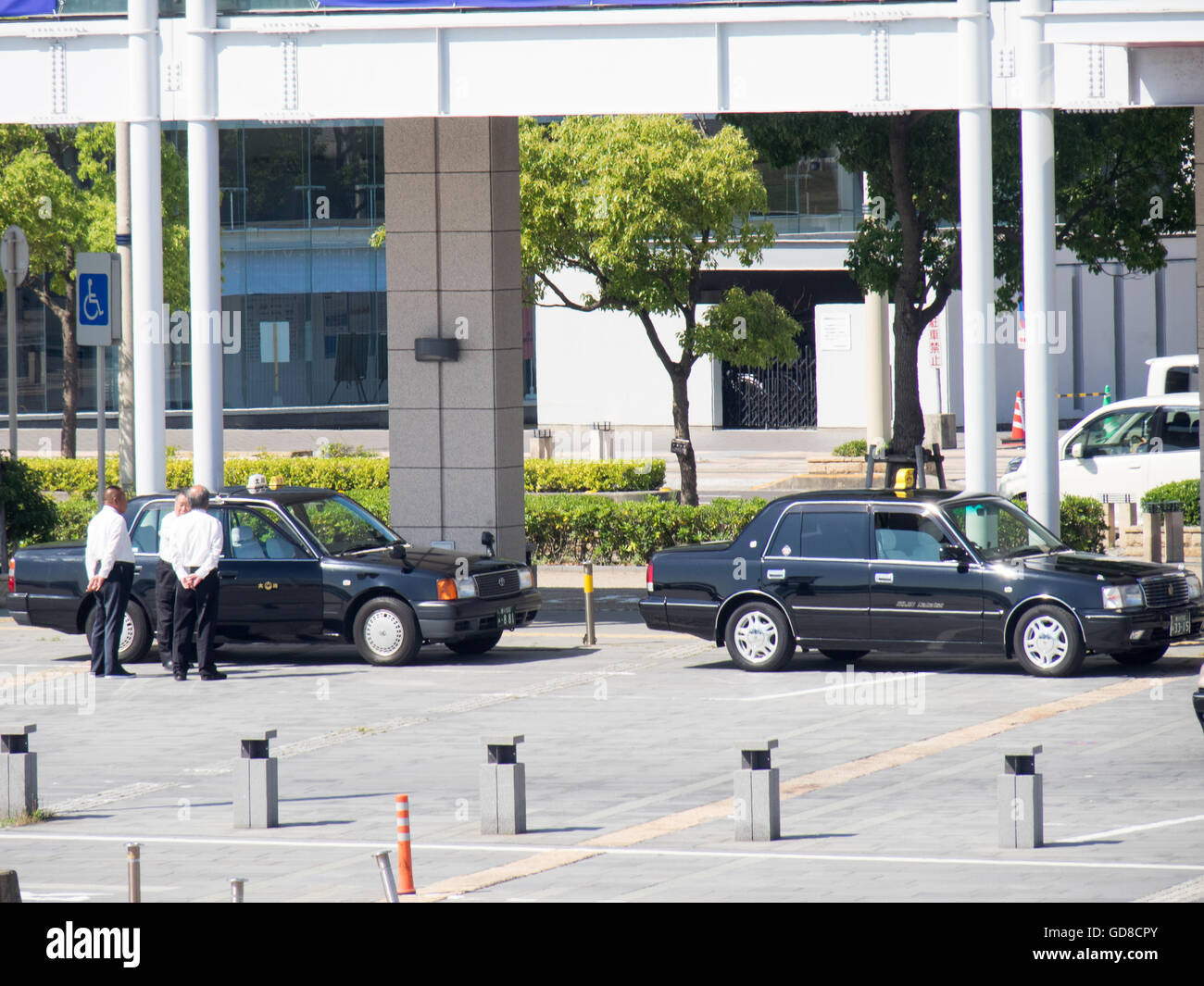 Male taxi drivers talking and standing together beside their taxis on