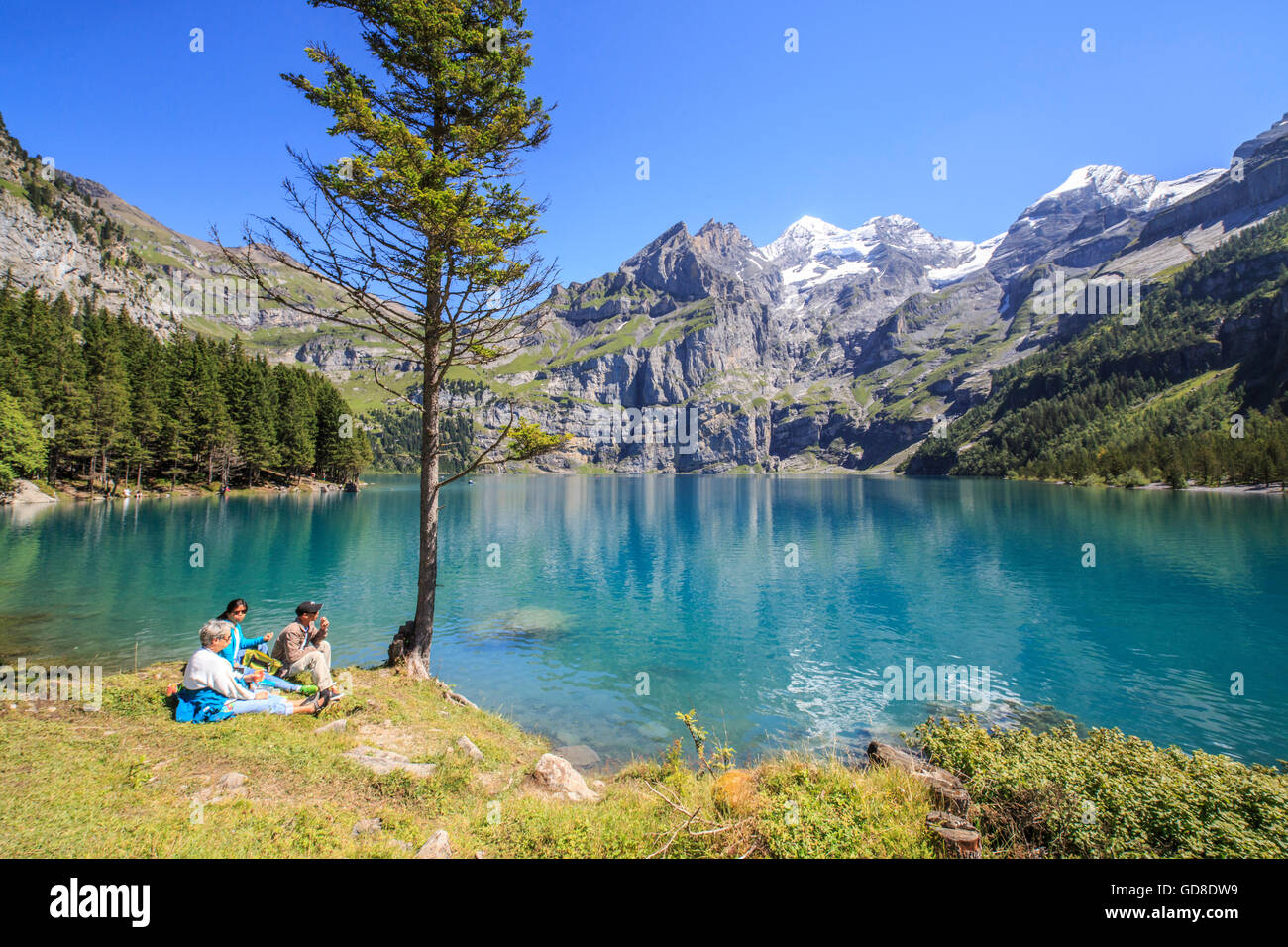 Hikers admire Lake  Oeschinensee Bernese Oberland Kandersteg Canton of Bern Switzerland Europe Stock Photo