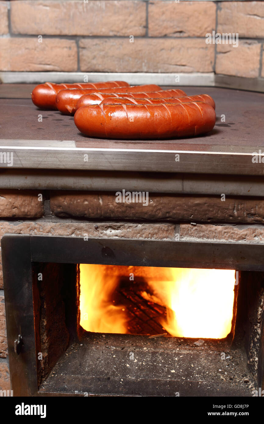 Grilling sausages on wood burning stove Stock Photo Alamy
