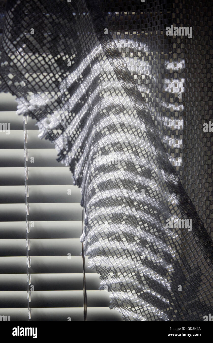 Sunlight streaming through Venetian blinds cast a pattern of light and shadow on a bathroom curtain Stock Photo