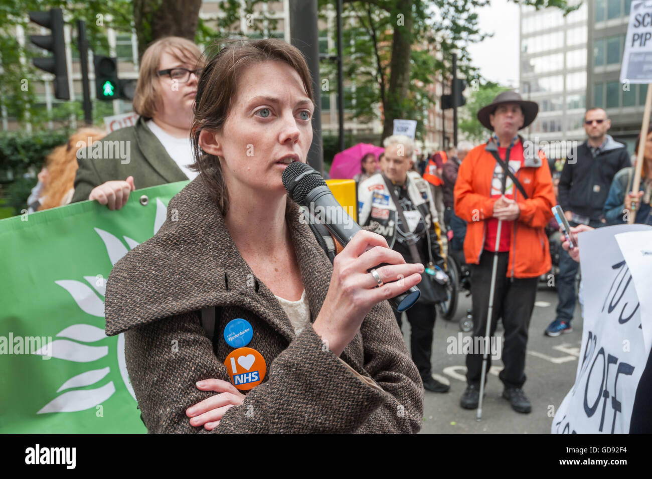 London, UK. 13 July 2016. Junior doctor Aislinn Macklin-Doherty speaks on Victoria St, which is blocked by disabled protesters outside the offices of Capita PLC over the removal of vital support which enables them to work and live on more even terms. The change from Disabled Living Allowance (DLA) to Personal Independence Payment (PIP) and shoddy assessments by Capita and Atos, many of which are overturned at tribunals months later, has led to many losing essential support. Peter Marshall/Alamy Live News Stock Photo