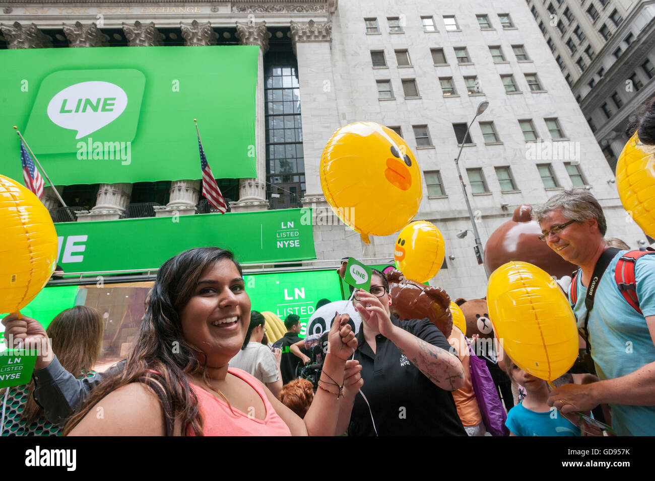 New York, USA. 14th July, 2016. Hordes of visitors clammer for free balloons with faces representing Line 'stickers' in front of the New York Stock Exchange decorated for the Japanese messaging company Line's initial public offering on Thursday, July 14, 2016. Line Corp., a popular messaging app in Japan is owned by South Korean Naver Corp. Line has 218 million active users monthly, with Japan, Taiwan and Indonesia accounting for two-thirds of them.  Credit:  Richard Levine/Alamy Live News Stock Photo
