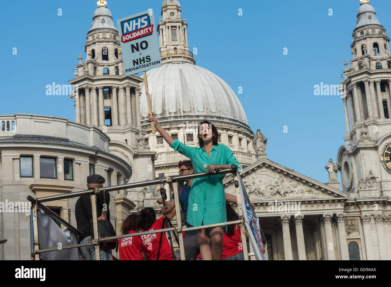 London, UK, 14th July 2016.  Junior doctor Aislinn Macklin-Doherty, one of the organisers of the event by NHS solidarity, a group of healthcare workers and supporters dedicated to saving a publicly funded, delivered and accountable NHS waves a placard on top of the FBU fire engineas it approaches St Paul's  Cathedral. Peter Marshall/Alamy Live News Stock Photo