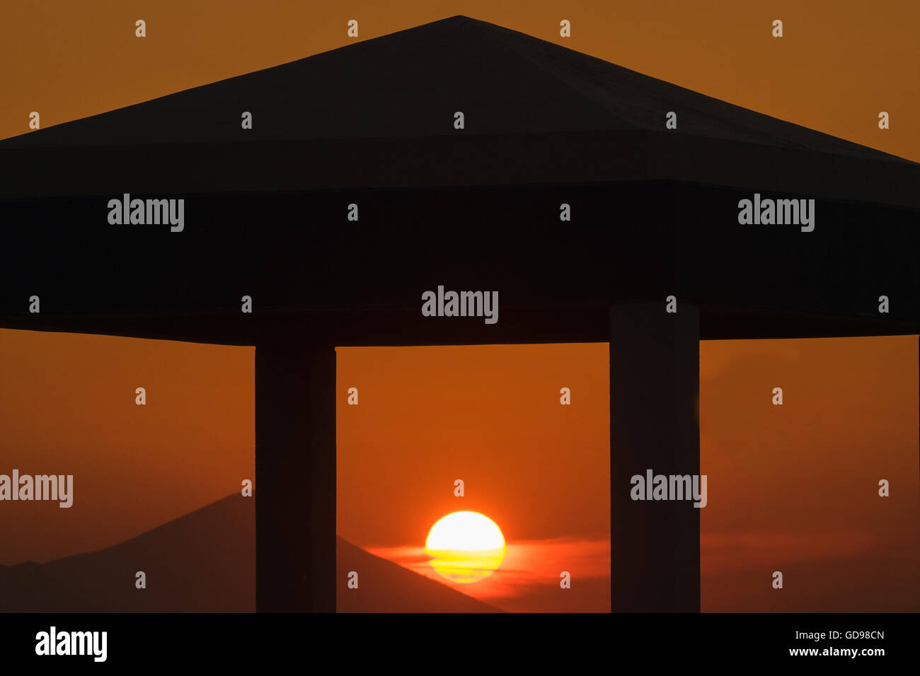 Sunset at Kalamos village in Greece. Sun is framed through the columns of a building. Stock Photo