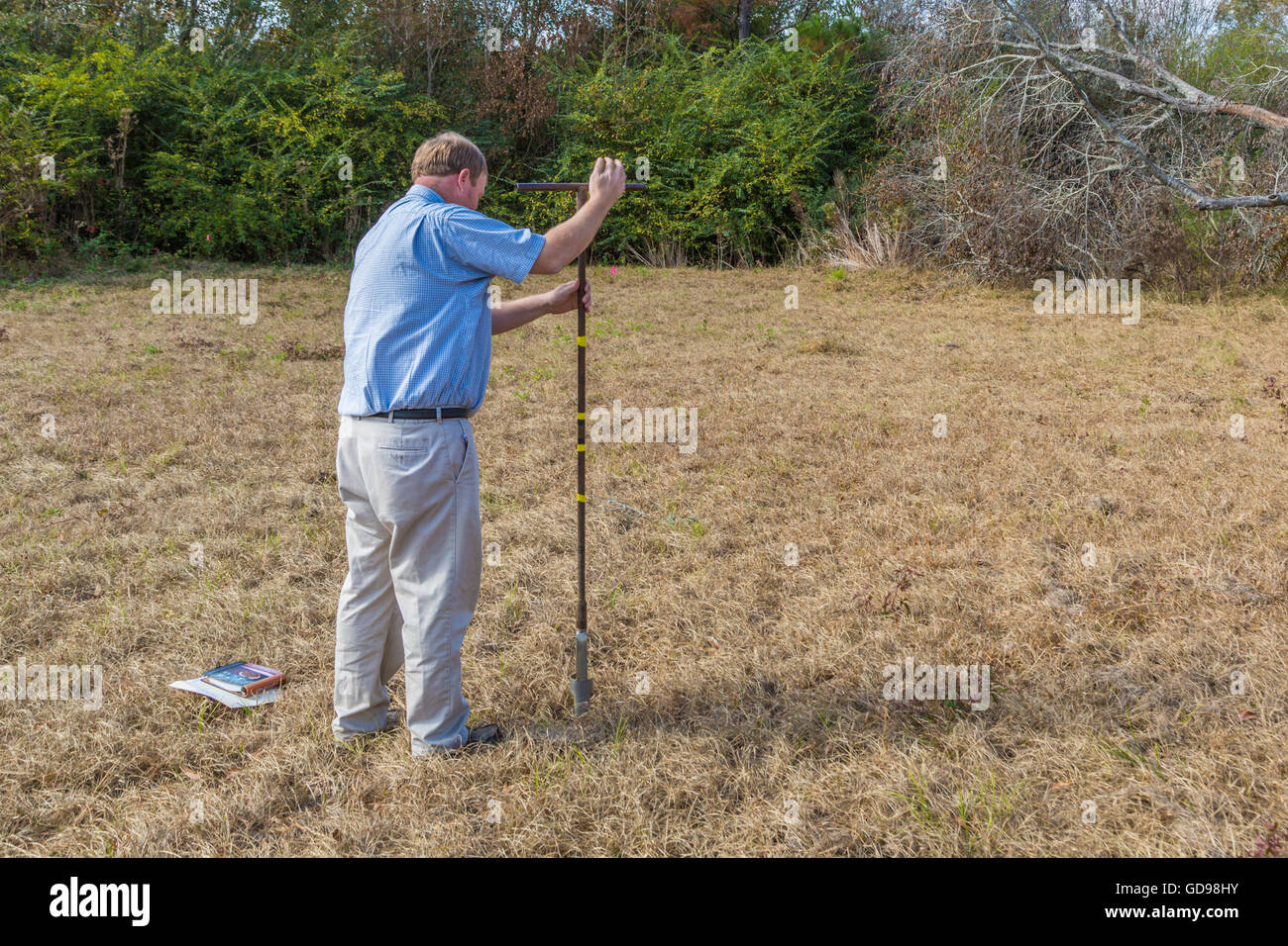Man performing a perc test to determine if soil is appropriate for an underground septic system Stock Photo