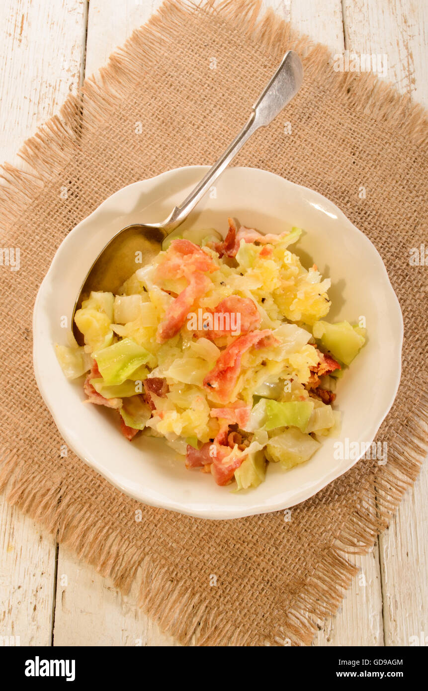 irish colcannon, made with mashed potato, cabbage, grilled bacon and crushes peppercorn in a bowl, with spoon Stock Photo