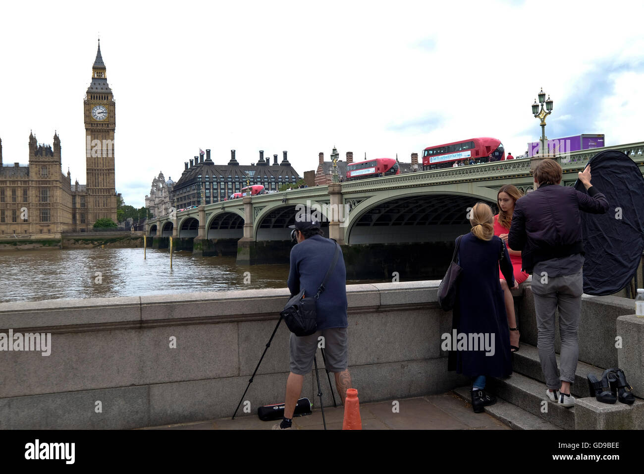 A photographer doing a fashion shoot with Westminster Bridge Bridge and the Houses of Parliament a London landmark in the background Stock Photo