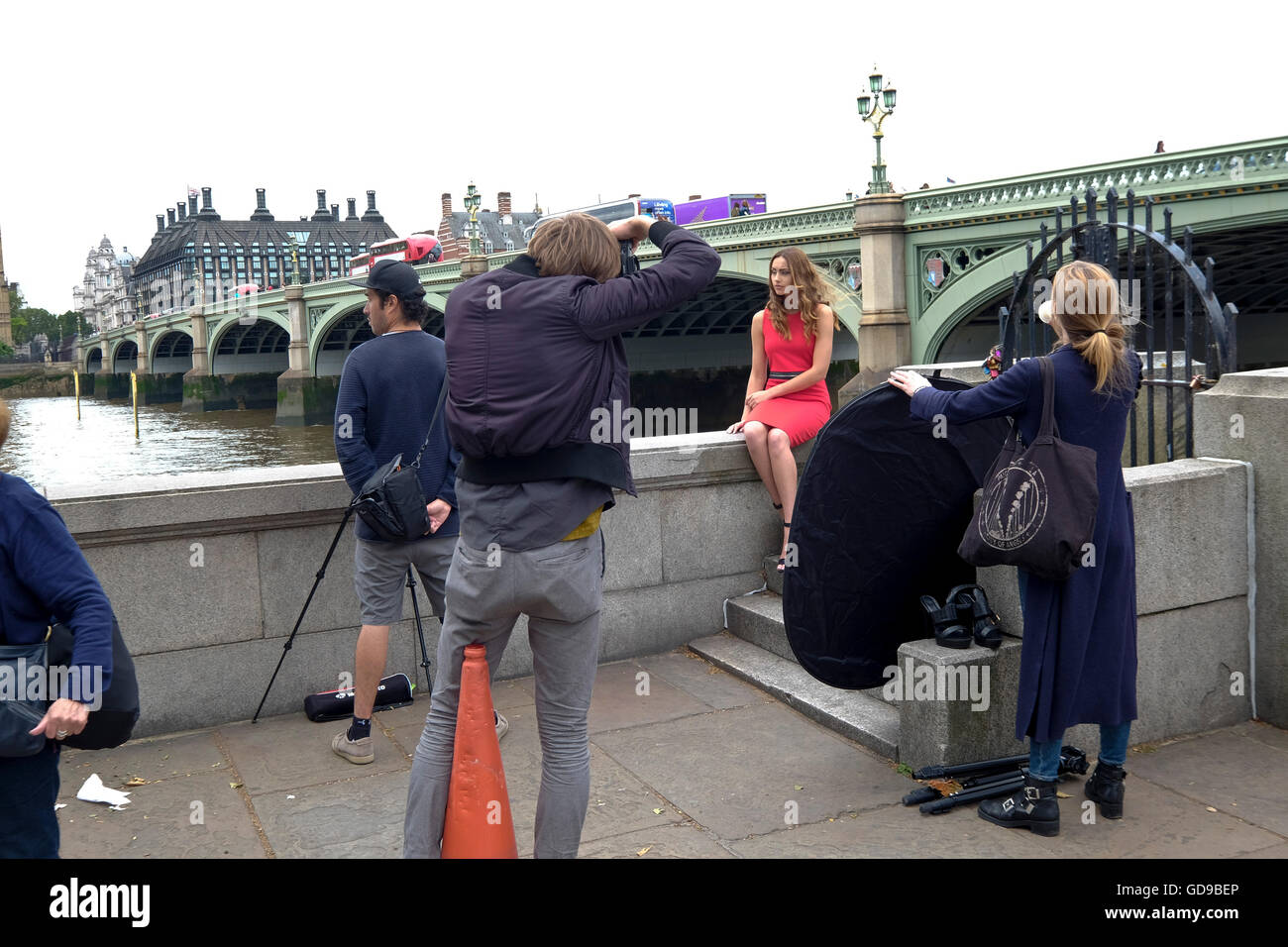 A photographer doing a fashion shoot with Westminster Bridge a London landmark in the background Stock Photo