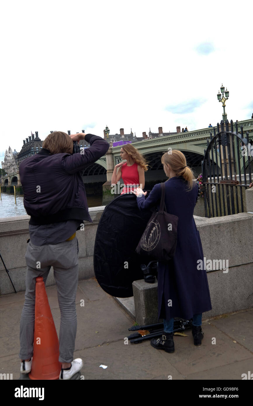 A photographer doing a fashion shoot with London Bridge a London landmark in the background Stock Photo