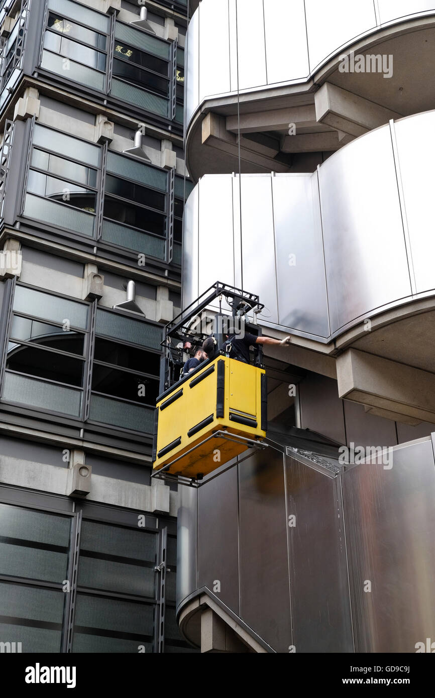 Cleaners in a cradle cleaning the stainless steel facade ...