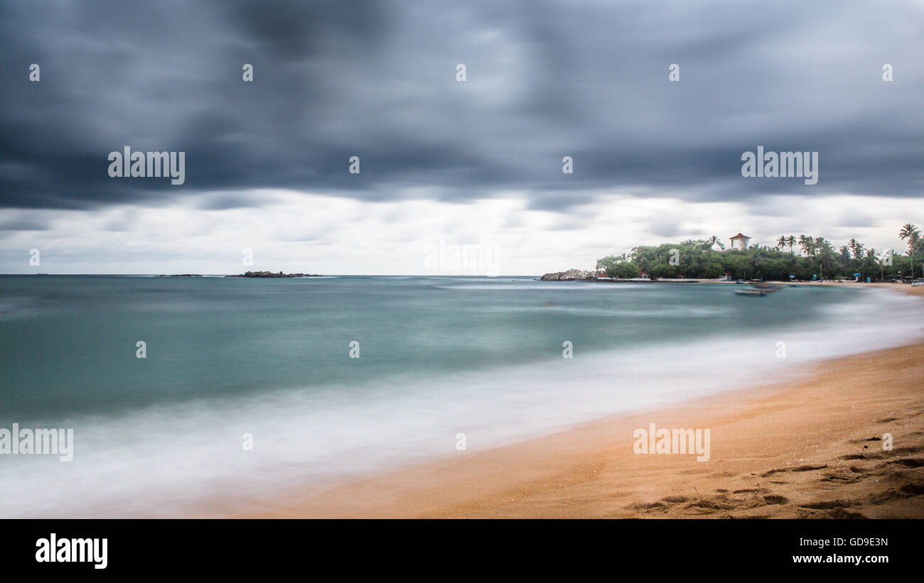Long exposure shot of beach at Unawatuna, Sri Lanka during rainy season with grey clouds. Stock Photo