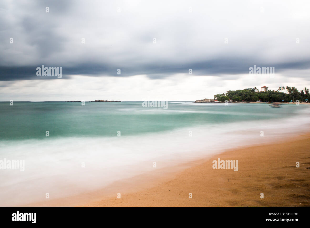 Long exposure shot of beach at Unawatuna, Sri Lanka during rainy season with grey clouds. Stock Photo