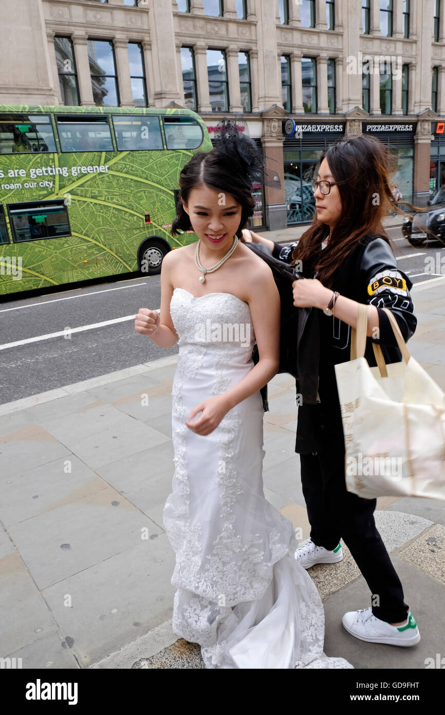 A Chinese bride having her wedding photographs taken in the City of London is fussed over by her stylist Stock Photo