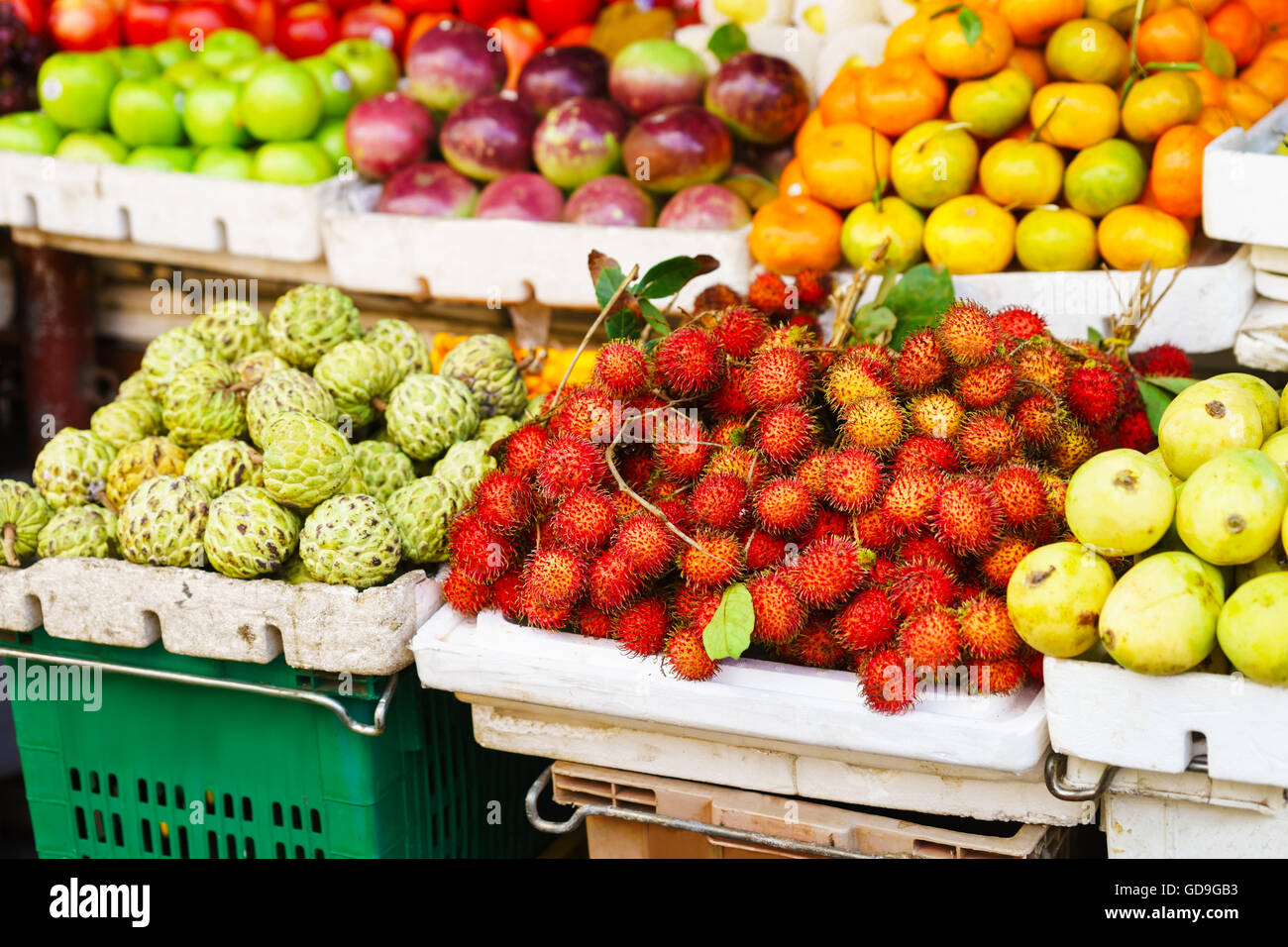Asian street farmer market selling fresh fruit and berry in Hoi An, Vietnam. Passion fruit, litchi, cherimoya, mango and other. Red, orange and green colors. Stock Photo