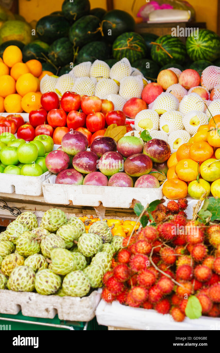 Asian street farmer market selling fresh fruit and berry in Hoi An, Vietnam. Passion fruit, litchi, cherimoya, mango and others. Red, orange and green colors. Stock Photo