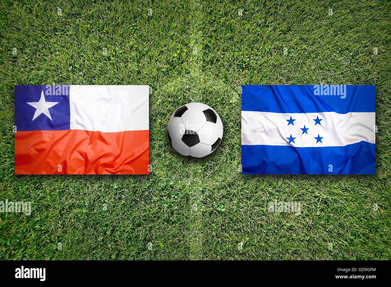 Chile vs. Honduras flags on green soccer field Stock Photo