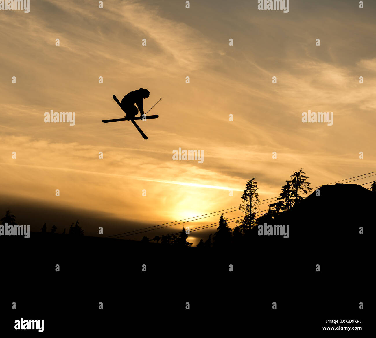 Skier doing a grab off  jump in the sunset Stock Photo