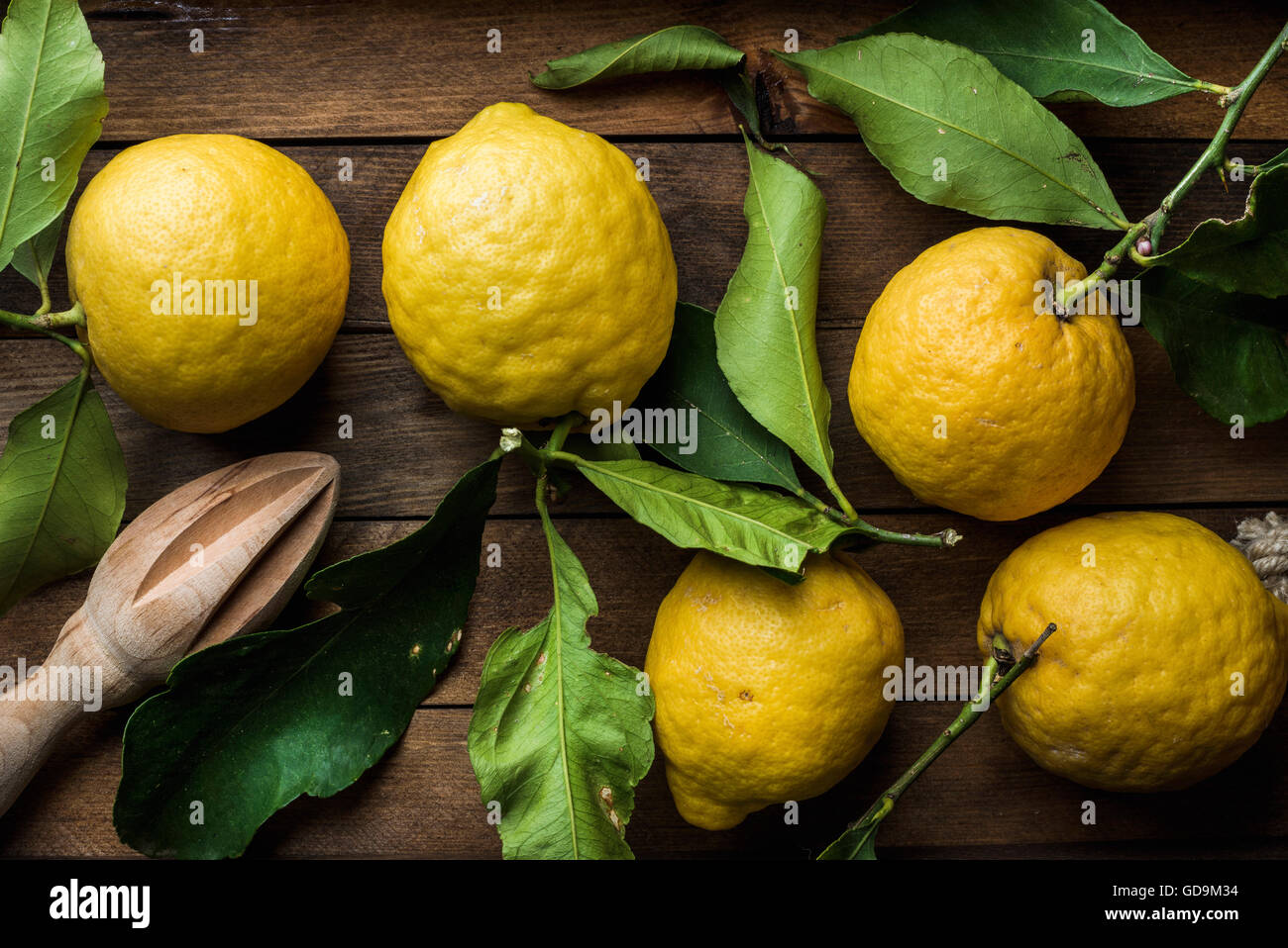 Frsh lemons with leaves on wooden background, top view, horizontal composition Stock Photo