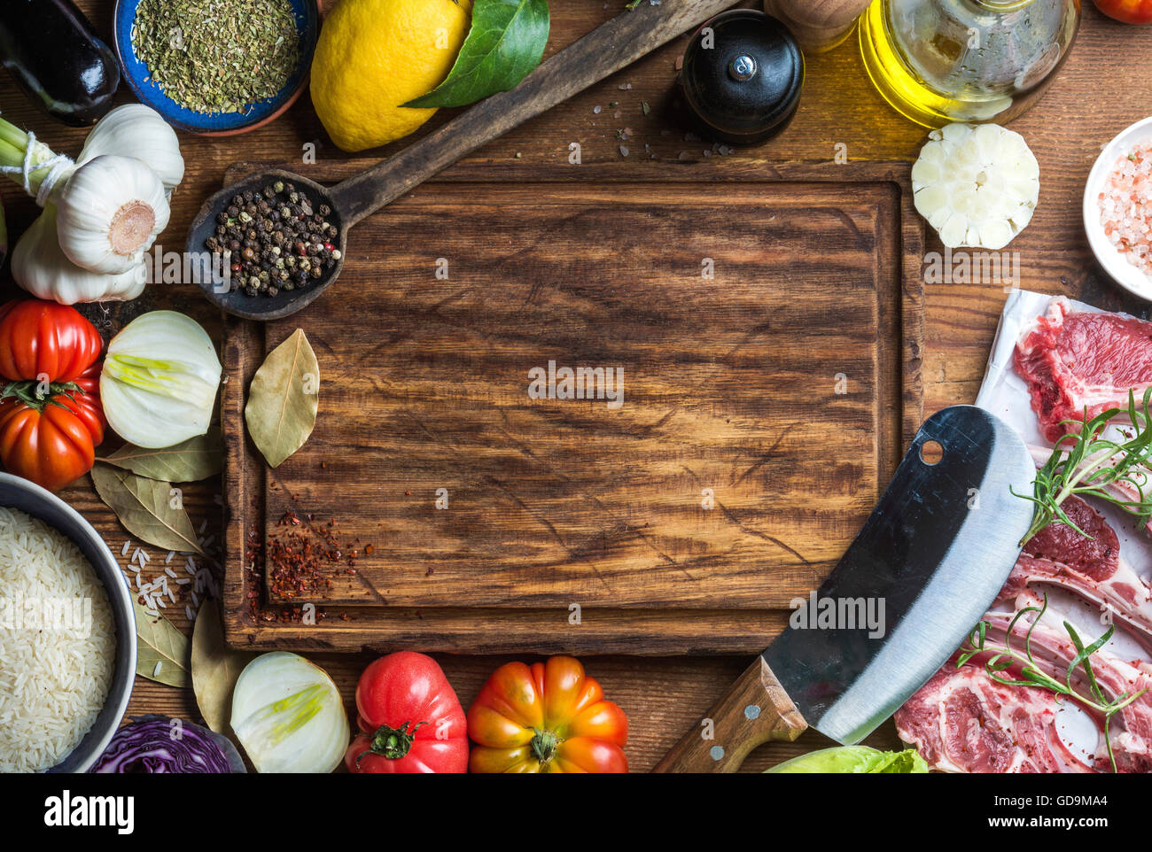 Ingredients for cooking healthy meat dinner. Raw uncooked lamb chops with vegetables, rice, herbs, olive oil and spices over rus Stock Photo