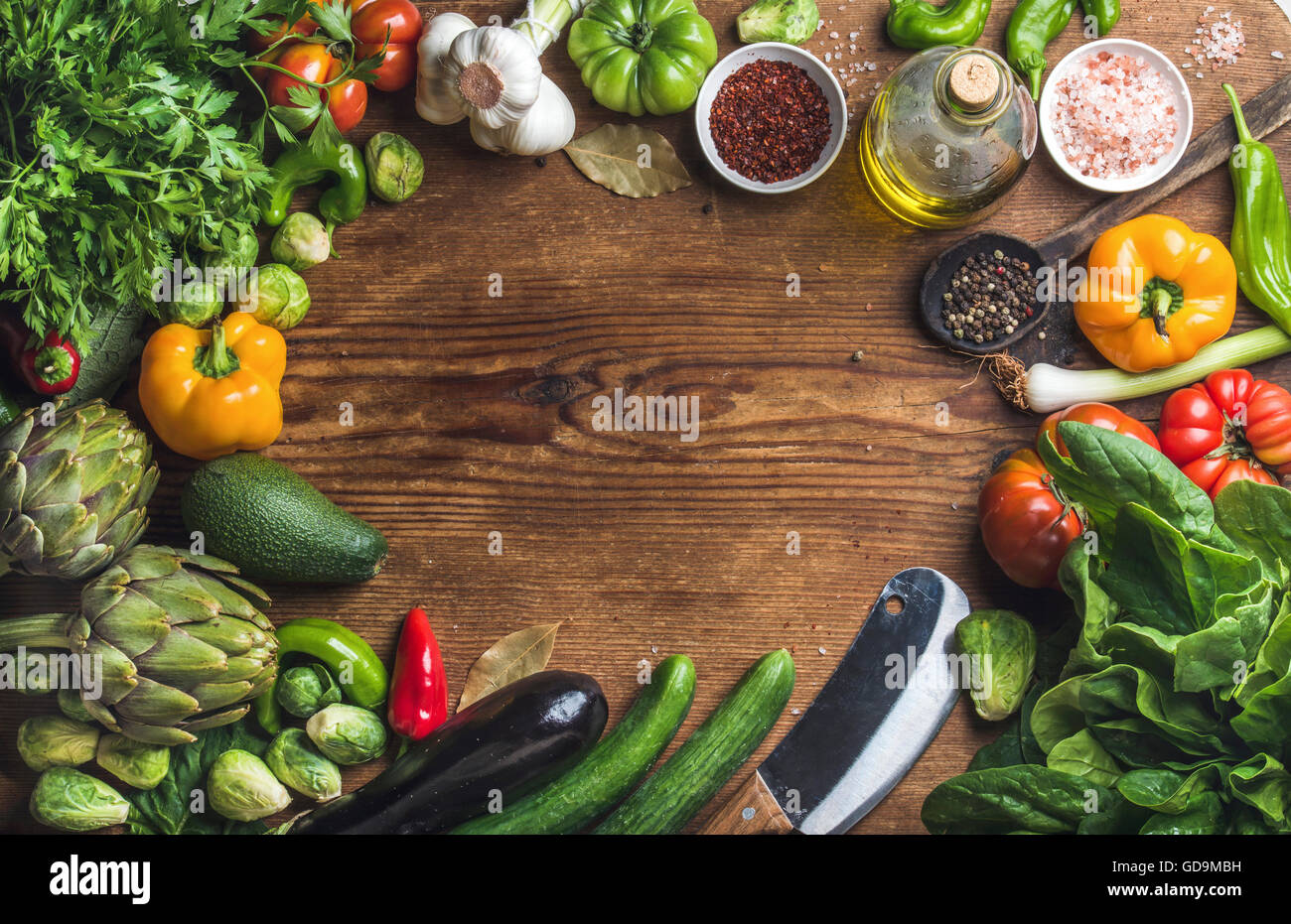 Ingredients for cooking healthy vegetarian cooking. Variery of vegetables, spices, herbs and olive oil over wooden background, t Stock Photo