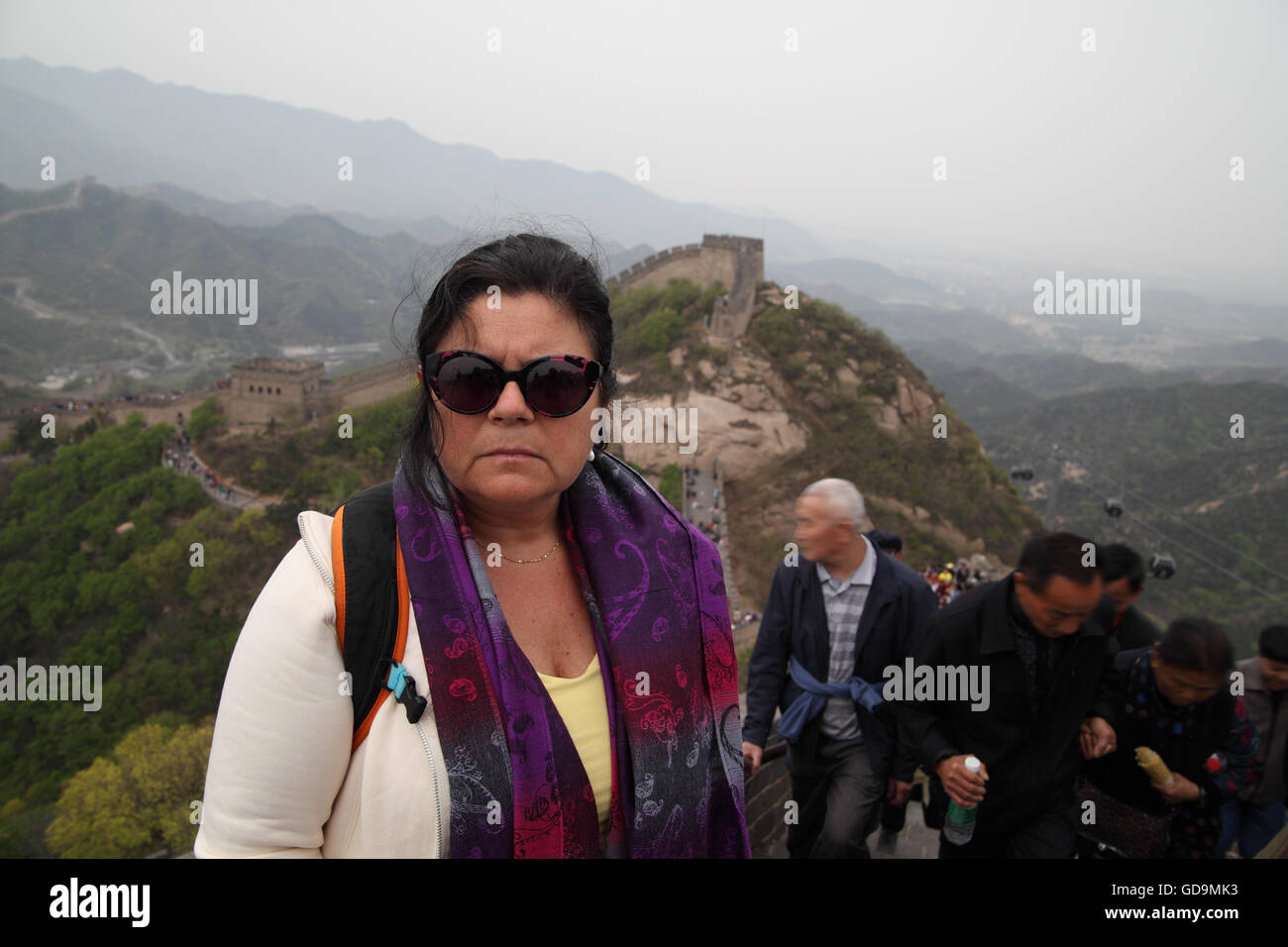 A senior Israeli tourist (57) pauses for a little rest while she and many other unrecognizable tourists climb the Great Wall Stock Photo